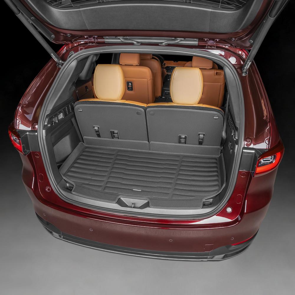 Open trunk of a car with brown seats and a gray floor mat on a dark background