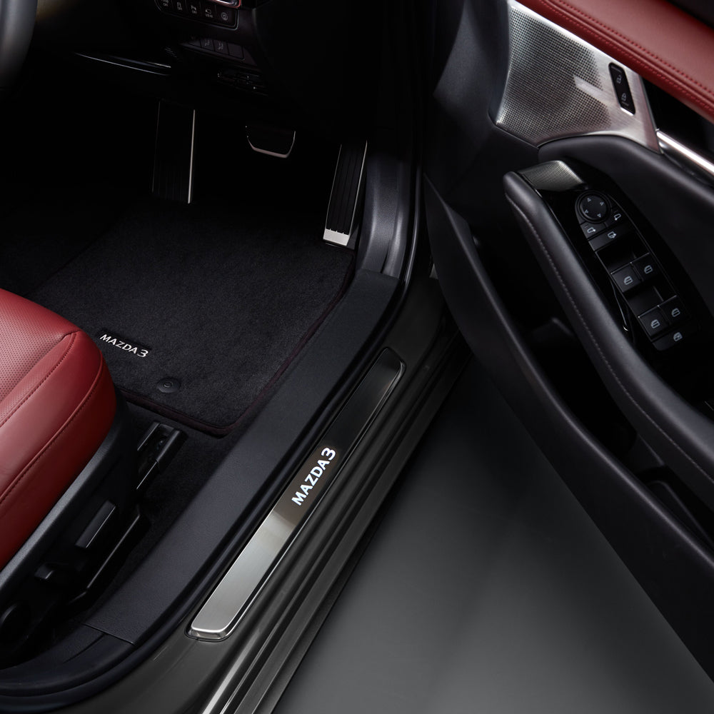 Car interior with red seat and 'MAZDA' branding on door sill and floor mat.