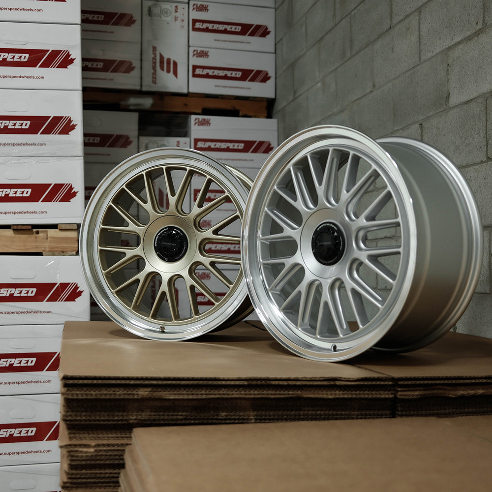 Two alloy wheels on a cardboard box with SuperSpeed boxes stacked in the background.