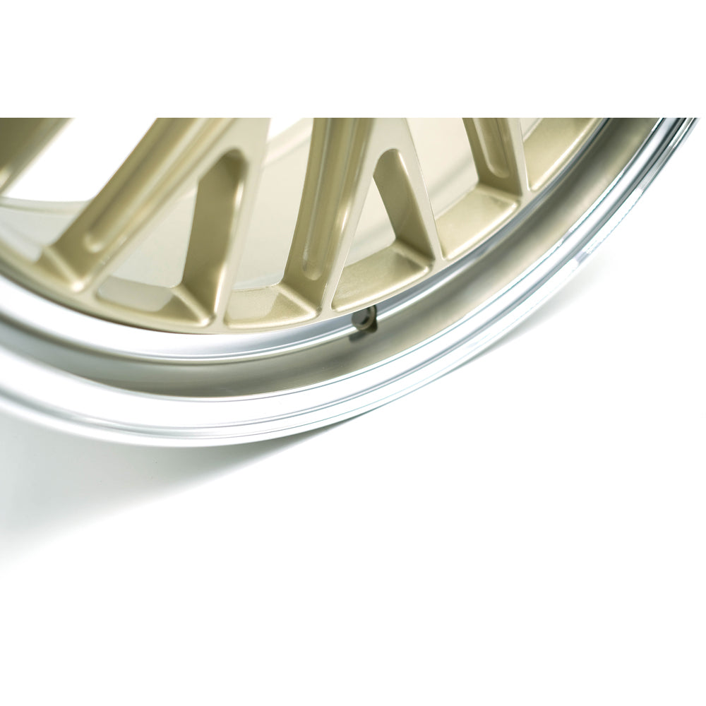 Close-up of a gold and silver alloy wheel rim on a white background